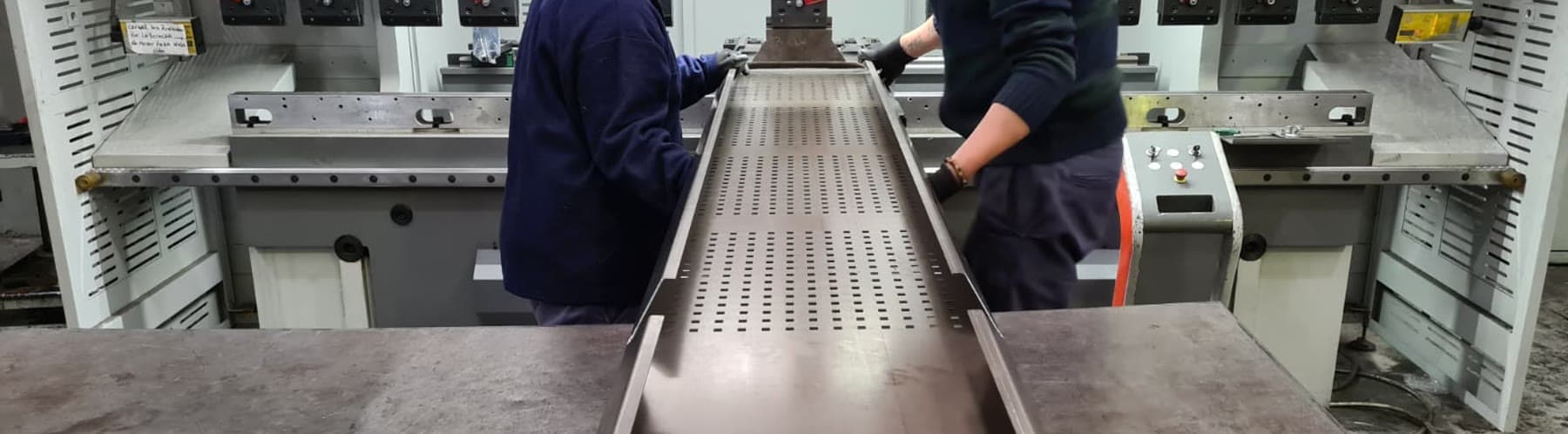 Dos operarios de Oxpane retirando una bandeja perforada recién plegada en una plegadora CNC Bystronic.