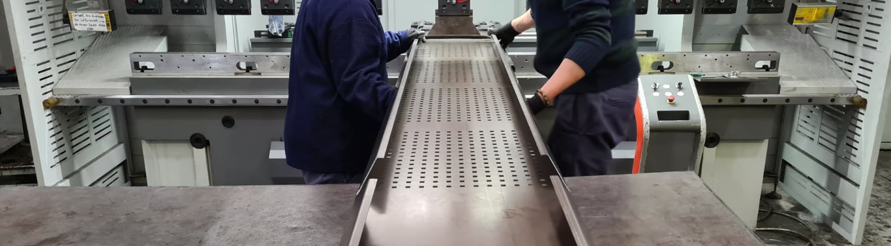 Dos operarios de Oxpane retirando una bandeja perforada recién plegada en una plegadora CNC Bystronic.